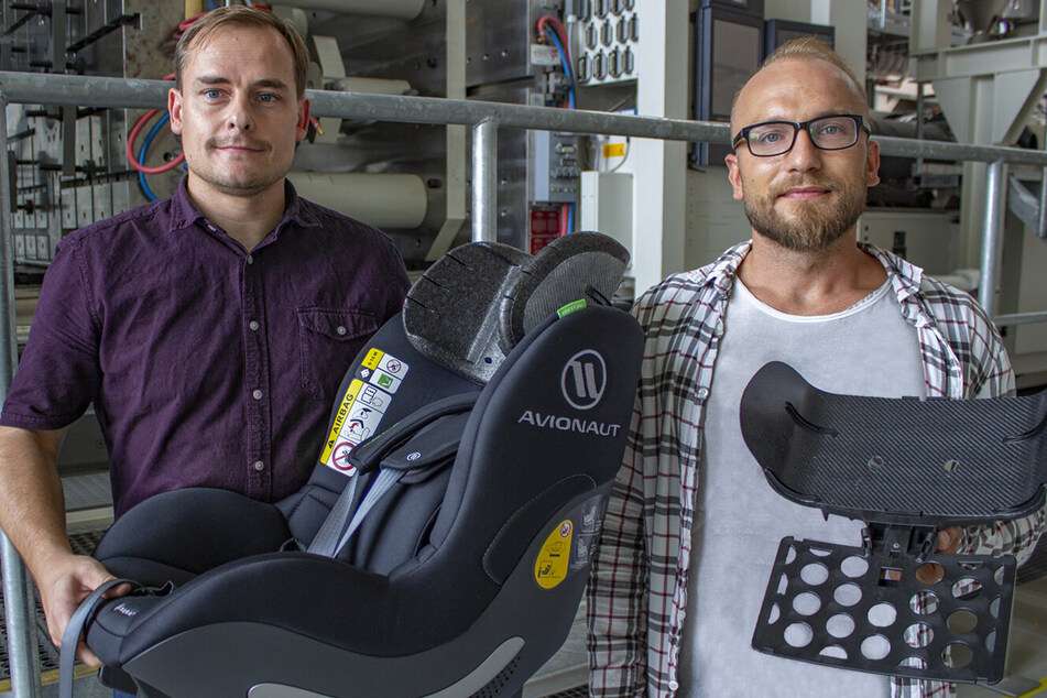 Die TU-Forscher Norbert Schramm (37, l.) und Tomasz Osiecki zeigen einen Kindersitz mit eingebauter Kopfstütze sowie die Organoblech-Preform mit Trägerplatte.