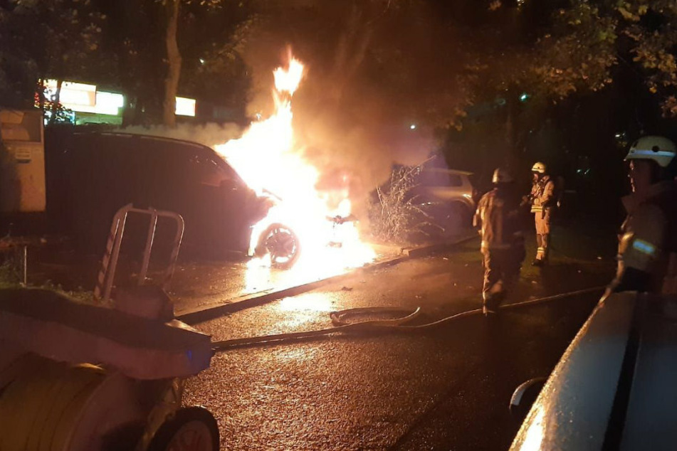 Einsatzkräfte der Feuerwehr löschen ein Auto in Berlin-Prenzlauer Berg.