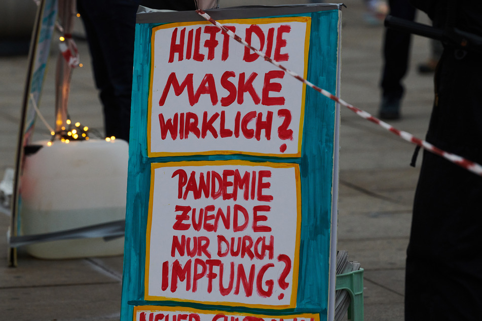 "Hilft die Maske wirklich? Pandemie zu Ende nur durch Impfung?" steht auf einem Aufsteller auf der Demonstration gegen die Corona-Einschränkungen.