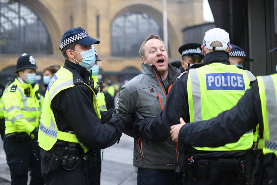 Ein Mann wird während einer Demonstration gegen die Corona-Beschränkungen von Polizisten weggeführt. Bei Protesten gegen die Corona-Beschränkungen hat die Polizei in London mehr als 60 Menschen festgenommen.