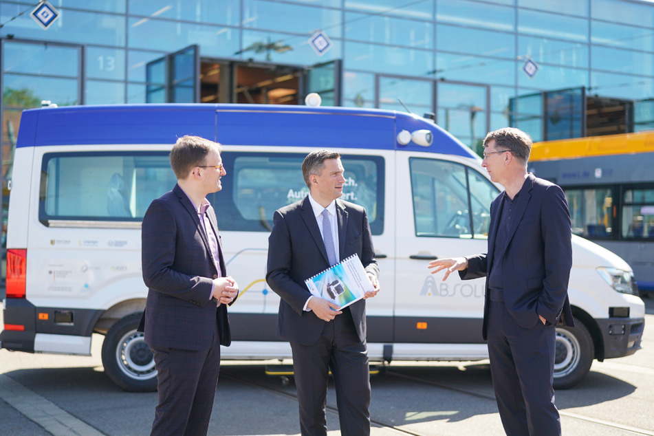 Sachsens Wirtschaftsminister Martin Dulig (47, SPD, M.) spricht mit dem Leipziger Verkehrsbetriebe-Chef Ulf Middelberg (54, r.) und Studien-Autor Robert Peters vor einem bislang nicht zugelassenen Kleinbus-Prototypen, der für autonomes Fahren ausgerüstet wird.