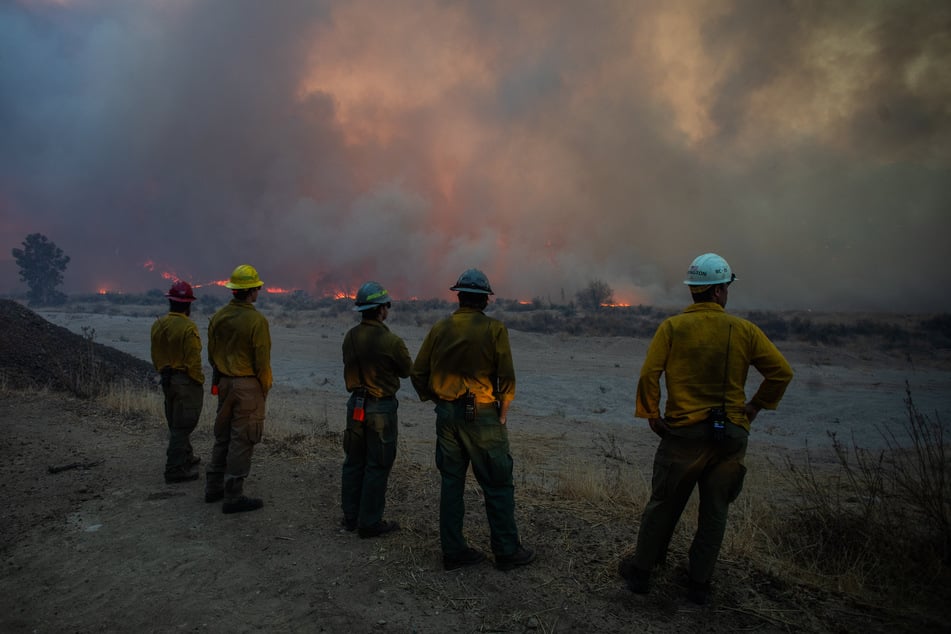 Firefighters watch the Hughes Fire burn in the distance in Castaic, a neighborhood in northwest Los Angeles County, California, on January 22, 2025.