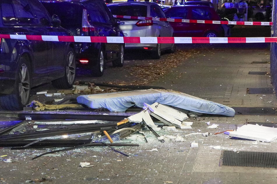 Die Trümmerteile verteilen sich über den Gehweg vor dem Gebäude.