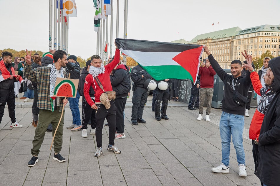 Demonstranten halten trotz eines Verbots einer Pro-Palästinenser-Demonstration am Flaggenplatz am Jungfernstieg eine Palästina-Flagge hoch.