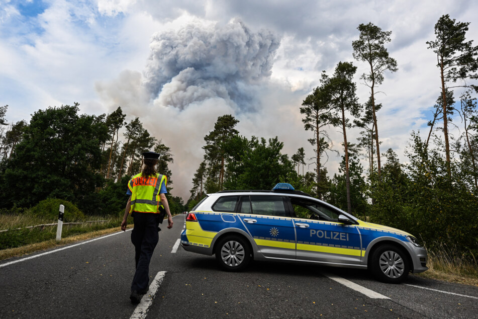 Ein Polizeiauto hat eine Straße im Waldbrandgebiet in der Gohrischheide abgesperrt.