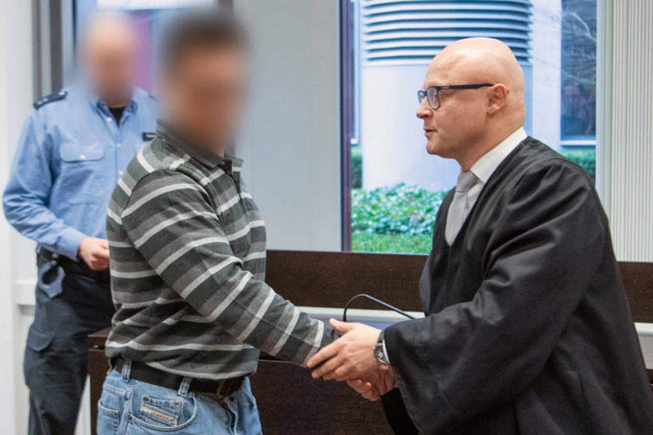 Der Angeklagter (M) wird beim Prozessbeginn im vergangenen Januar von seinem Rechtsanwalt Harald Roos (r) begrüßt.