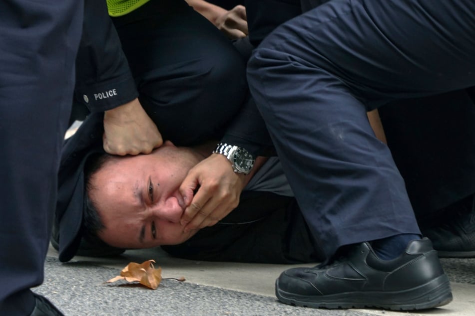 Polizisten zeigen einem Protestler in Shanghai deutlich, was sie von dessen Demo-Teilnahme halten.