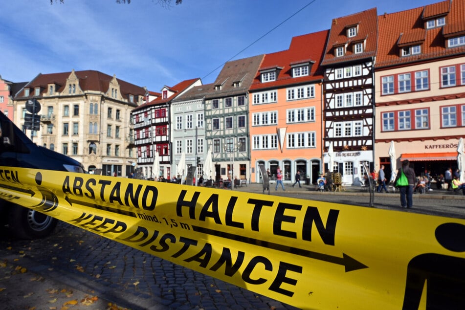 "Abstand halten!" in deutscher und englischer Sprache steht auf einem Flatterband am Domplatz inmitten der Erfurter Altstadt.