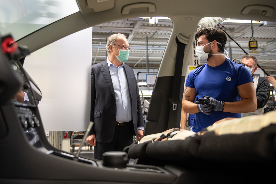 Stephan Weil (SPD, l), Ministerpräsident von Niedersachsen, und ein Mitarbeiter stehen mit einem Mund- und Nasenschutz in der Produktion von Volkswagen in Wolfsburg.