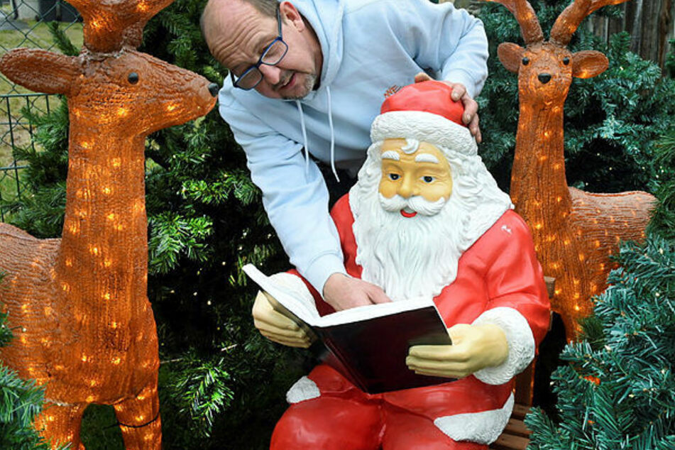 Ralf Müller kontrolliert in seinem weihnachtlich geschmückten Grundstück sein Märchenbild "Weihnachtsmann liest Bücher".