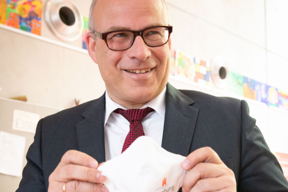 Ties Rabe (SPD) hält seine Mund-Nase-Bedeckung mit Hamburg-Logo.