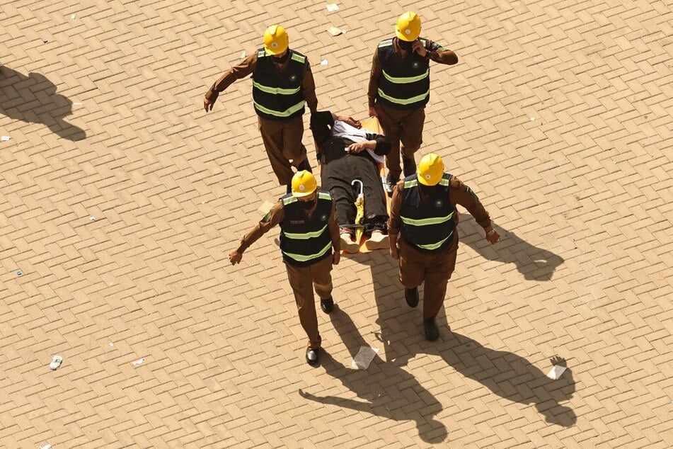 Rescuers carry away a man affected by the scorching heat on a stretcher as Muslim pilgrims arrive to perform the symbolic "stoning of the devil" ritual as part of the hajj pilgrimage in Mina on June 16, 2024.