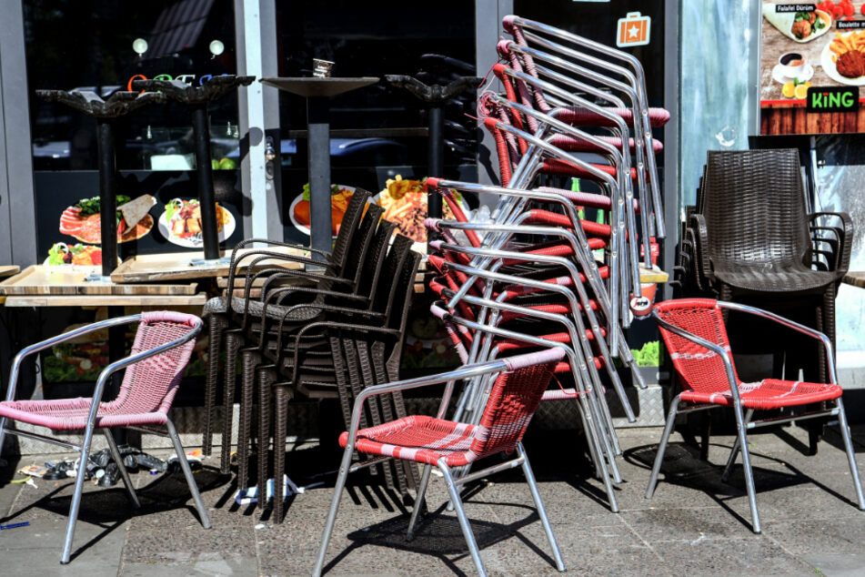 Vor einem geschlossen Imbiss in Berlin stapeln sich Stühle und Tische.