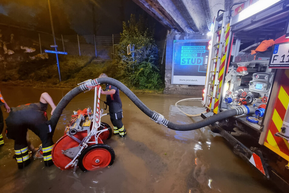 Feuerwehrleute pumpen Wasser aus einer Unterführung in München.