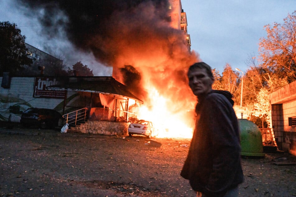 Ein Anwohner geht nach dem jüngsten Luftangriff in Kiew an einem Feuer vorbei.