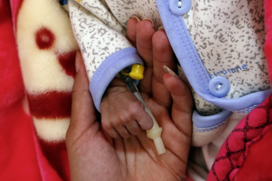 Eine Frau hält das winzige Händchen ihres Babys, das auf der Station für unterernährte Kinder in einem Krankenhaus medizinisch versorgt wird. (Archivbild)