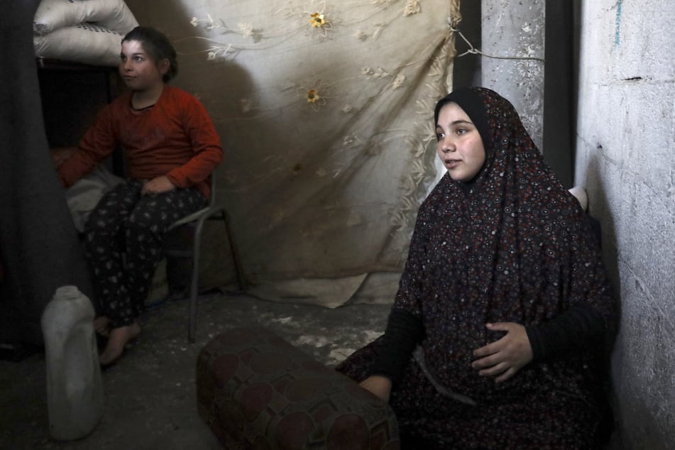 A pregnant Palestinian woman displaced from northern Gaza sits in a warehouse where she is taking shelter in Rafah, in the southern Gaza Strip, on February 29, 2024.