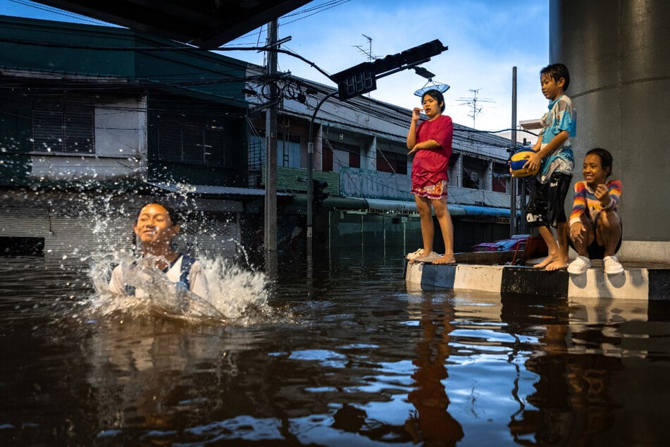 Kinder baden im Hochwasser von Bangkok.
