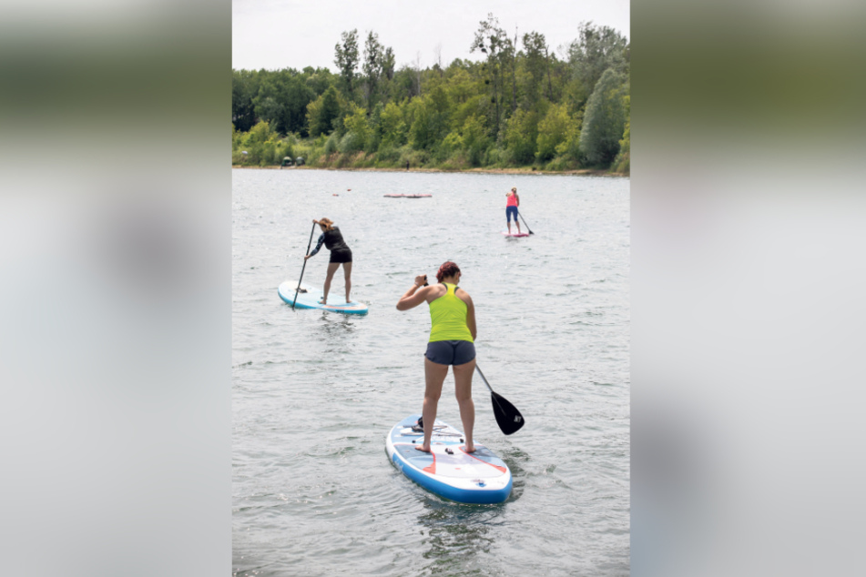 Auf einem weichem Surfbrett ("stand up paddle board") paddeln die Teilnehmer für die Übungen aufs Wasser.
