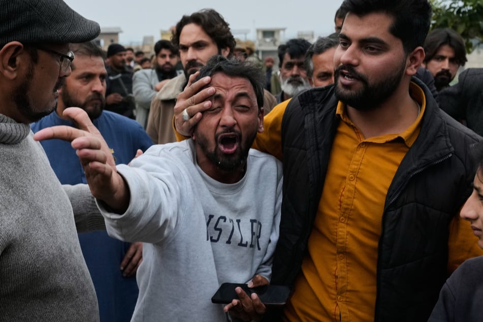 Menschen trösten einen Mann (M), der nach einem Anschlag auf ein schiitisches Gemeindehaus, um einen toten Verwandten trauert.