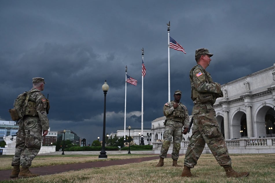 Members of the DC National Guard patrol outside Union Station as a storm approaches in Washington on August 17, 2025.