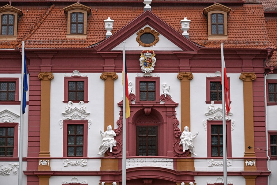 Fahnen hängen nass vor der Thüringer Staatskanzlei an Masten. In Thüringen müssen ab diesem Tag vor allen Landesgebäuden dauerhaft die Thüringen-, die Deutschland- und die Europaflagge wehen.