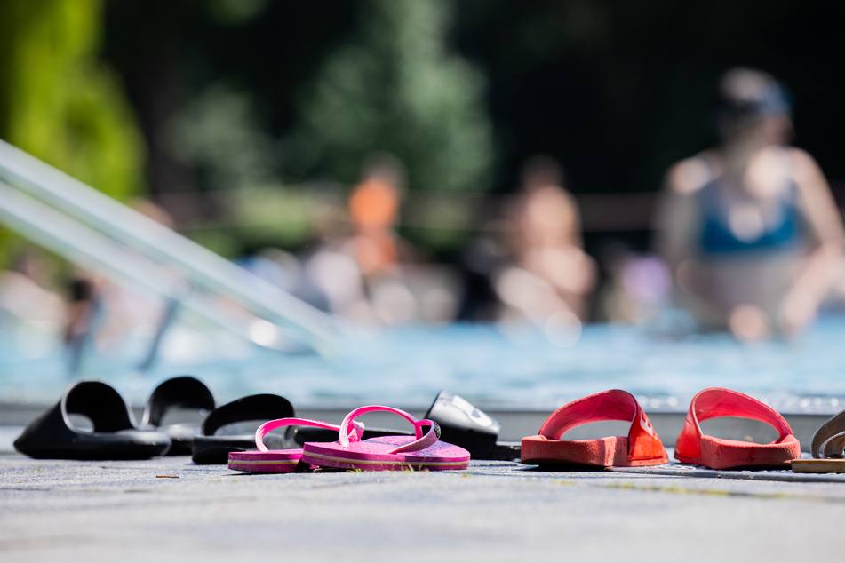 Menschen baden bei strahlendem Sonnenschein und blauem Himmel in einem Schwimmbecken des Kölner Stadionbads.