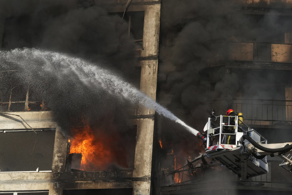 Feuerwehrleute arbeiten bei Löscharbeiten in einem durch Beschuss beschädigten Wohnhaus in Kiew.