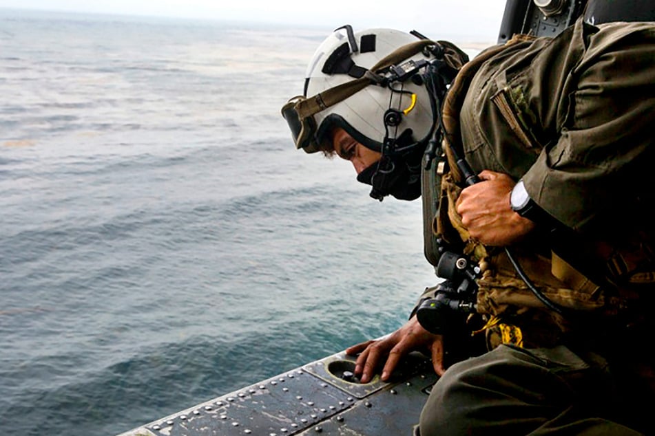Ein US-Marine blickt während einer Suchaktion nach vermissten US-Soldaten aus einem Hubschrauber der Navy.
