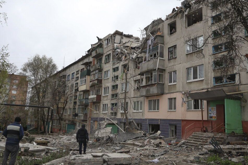 Menschen stehen vor einem beschädigten Gebäude nach einem Raketenangriff auf Slowjansk.