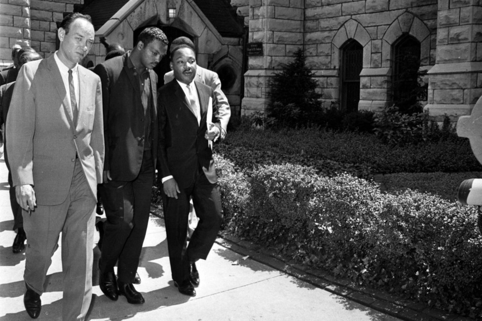 Jesse Jackson (c.) walking with Martin Luther King Jr. (r.) in 1966.