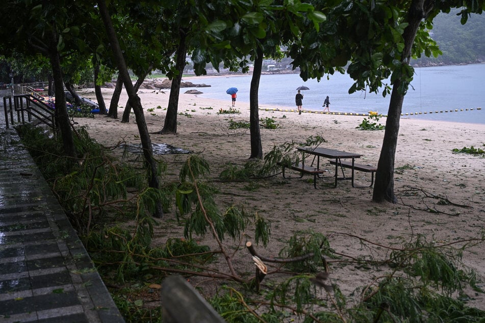 People walk on a beach with debris from Typhoon Noul which passed close to Hong Kong on July 26, 2026.