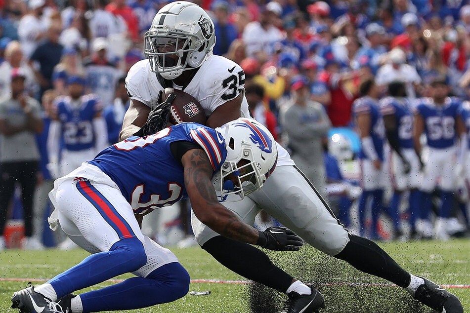 Zamir White of the Las Vegas Raiders gets tackled by Dane Jackson (l) of the Buffalo Bills during the fourth quarter at Highmark Stadium.