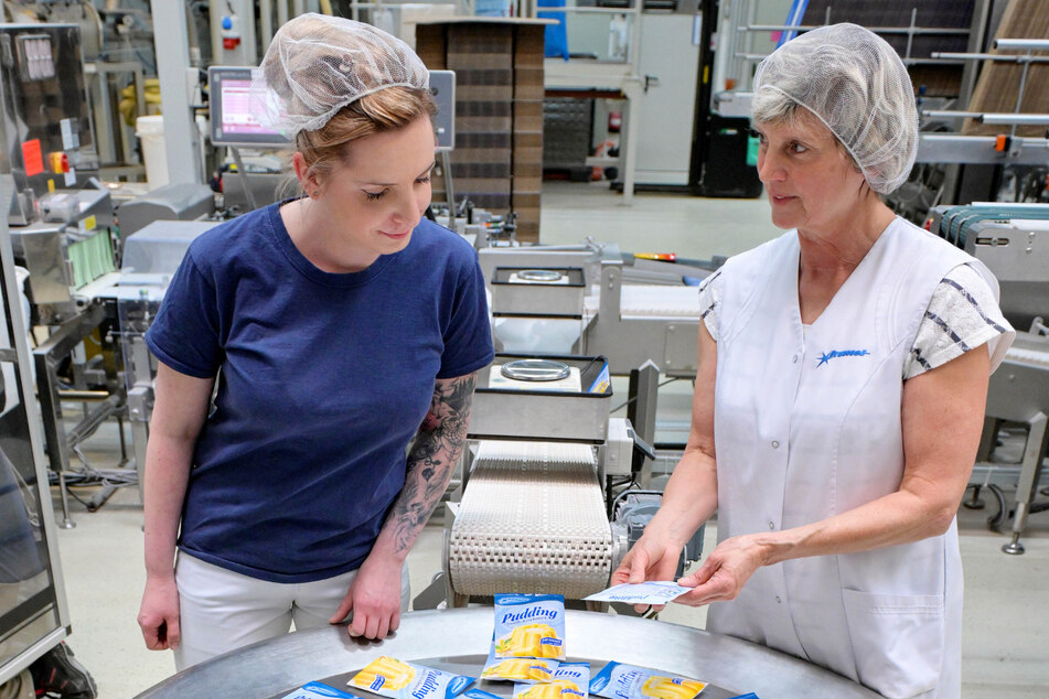 Geschäftsführerin Angela Pöhle und Anna Schulze (27) an einer Verpackungsanlage. Zum Sortiment gehören neben Eis und Pudding Back- und Dessertmischungen, Soßen und Tortenguss.