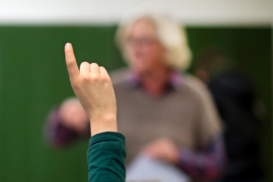 Ein Lehrer steht in einem Gymnasium an der Tafel.