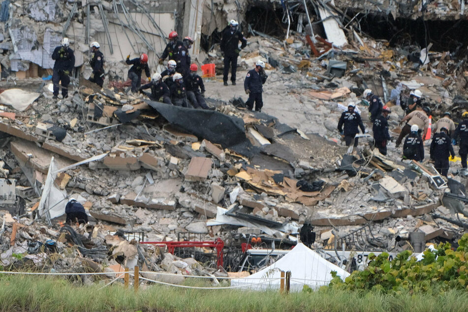 Rescue workers get ready to lift a yellow body bag with the remains of a victim.