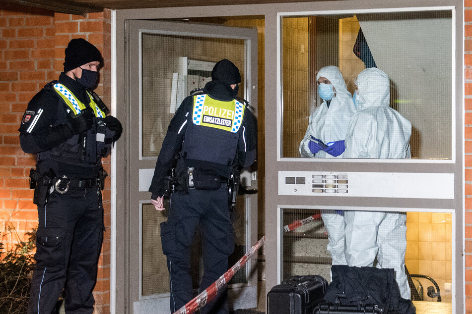 Polizisten und Mitarbeiter der Spurensicherung stehen im Stadtteil Neuallermöhe im Eingang eines Mehrfamilienhauses.