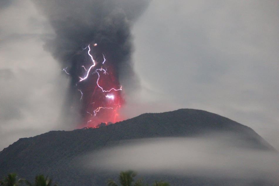 Lightning appears amid a storm as Mount Ibu spews volcanic material during an eruption.