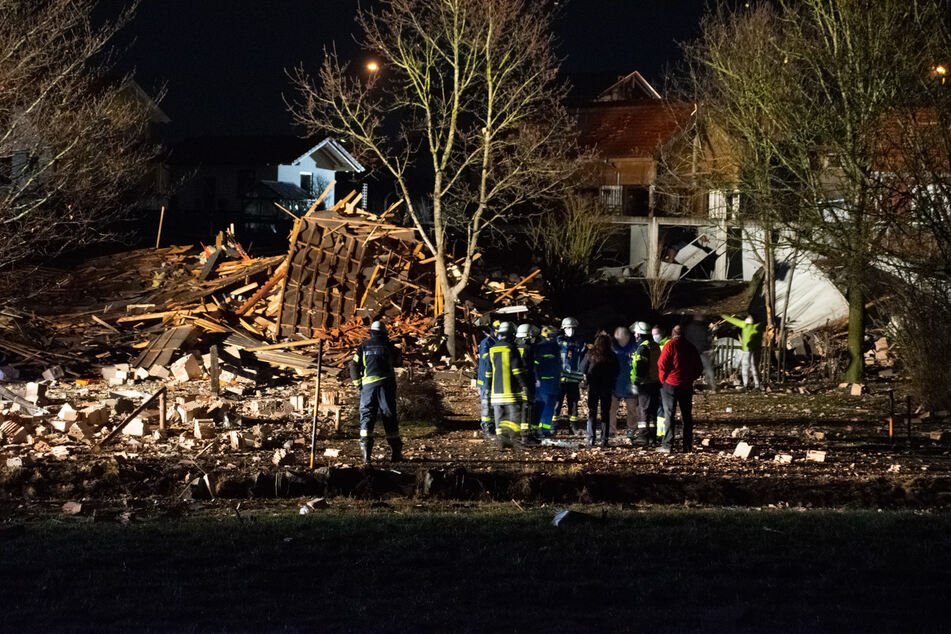 Einsatzkräfte stehen vor den Trümmern des Vereinsheims in Oberbeuren.