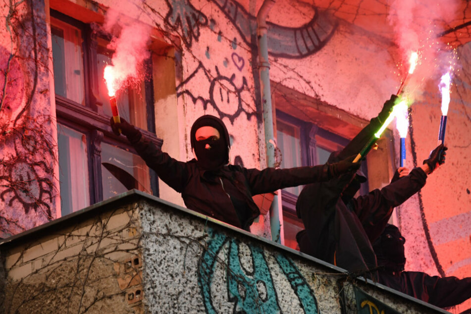 Unterstützer der linksradikalen "Revolutionären 1. Mai-Demonstration" stehen mit Pyrotechnik in den Händen auf einem Balkon in Friedrichshain.