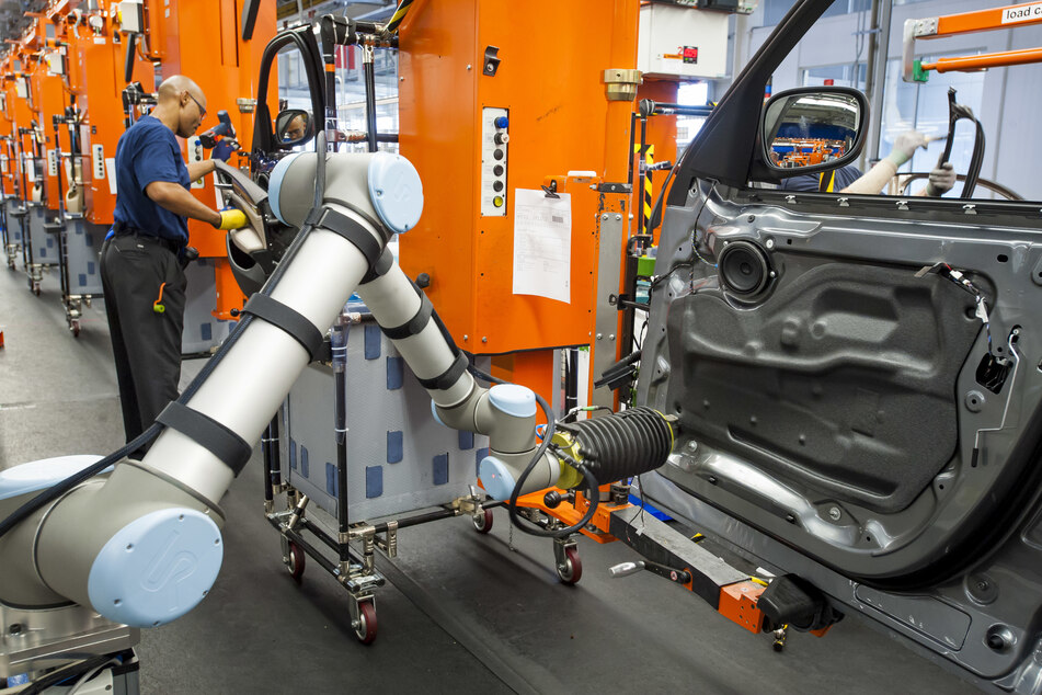 Ein Arbeiter steht neben einem Roboterarm an der Fertigungsstraße des BMW-Werks in Spartanburg, USA.