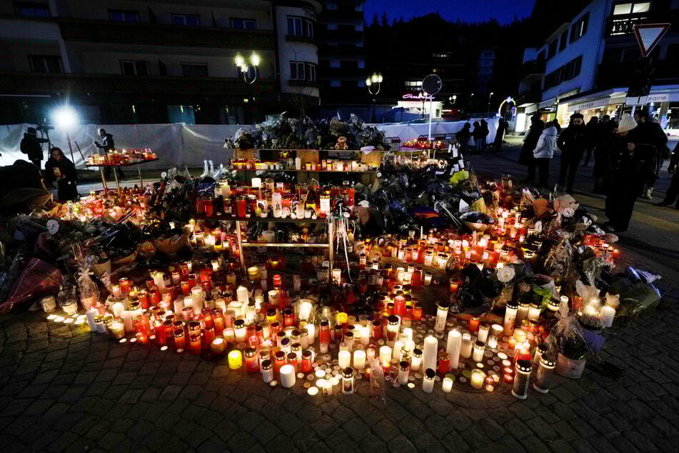 Die Anteilnahme ist groß: Menschen zünden Kerzen an und legen Blumen vor die versiegelte Bar Le Constellation in Crans-Montana.