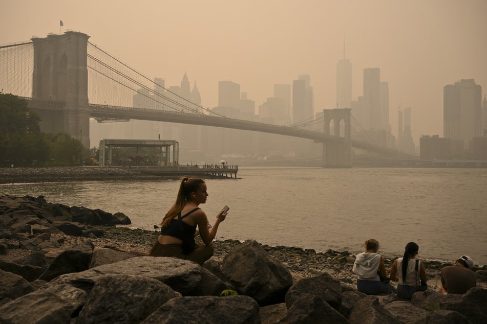 New Yorkers sit near Brooklyn Bridge as wildfire smoke from Canada smothered the city on Thursday, July 16.
