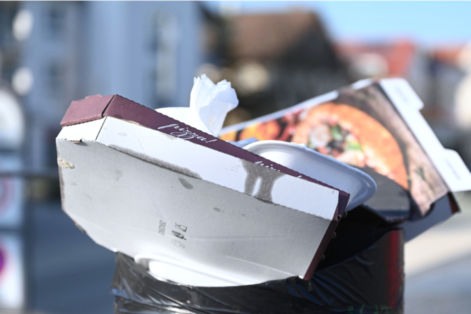 Pizzakartons und andere Essensverpackungen stecken in einem öffentlichen Mülleimer. Weil Restaurants und Cafés im Lockdown geschlossen sind, greifen immer mehr Menschen zu To-Go-Angeboten.