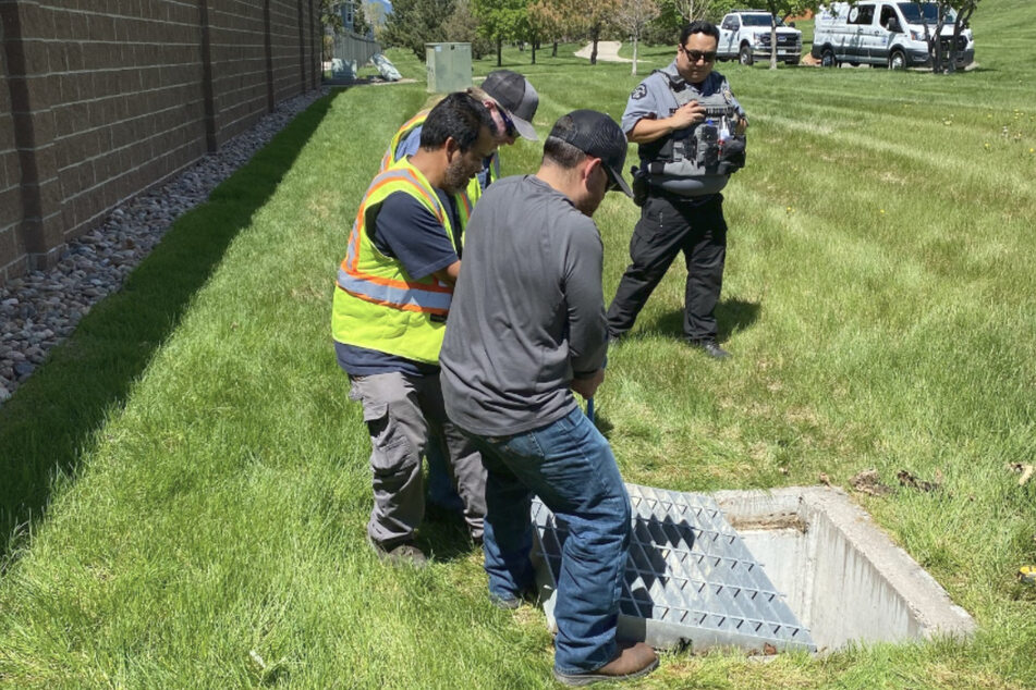 Helfer des "Broomfield Public Works and Utility Services" hoben das schwere Metallgitter an, unter dem sich der Hund in Not befand.