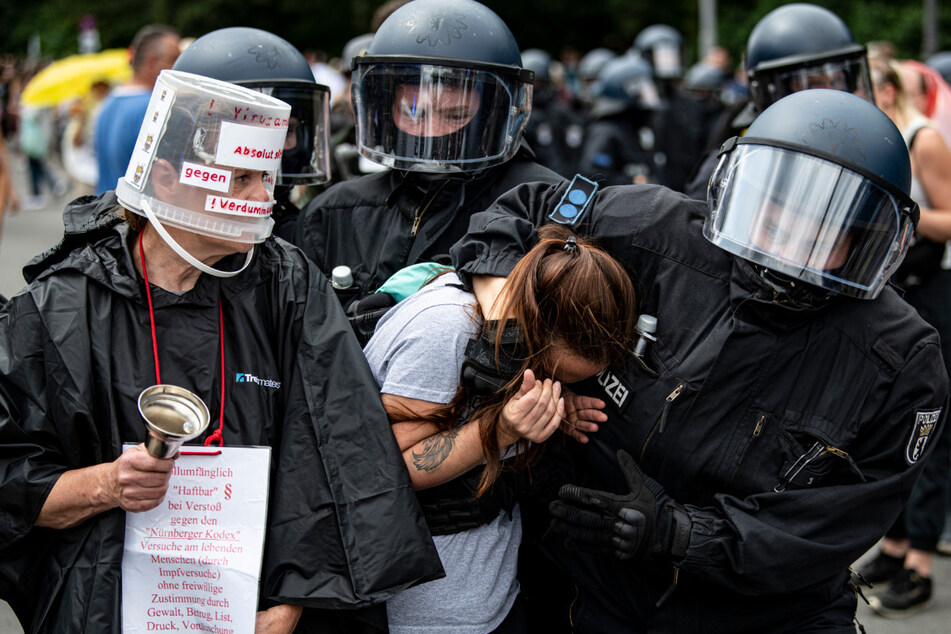 Polizisten nehmen eine Demonstrantin bei einer unangemeldeten Demonstration an der Siegessäule fest. Immer wieder kam es zu Auseinandersetzungen mit der Polizei, auch ein Journalist hat die Aggressivität zu spüren bekommen.