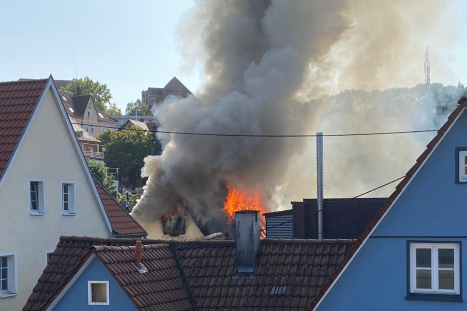 Zwischen den dicht nebeneinander gebauten Häusern schlagen Flammen in die Luft.