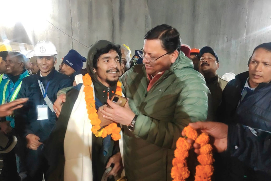Stolz nimmt Pushkar Singh Dhami (48, rechts) Ministerpräsident von Uttarakhand, einen der befreiten Arbeiter in Empfang.