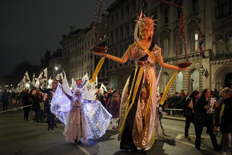 A gold-painted effigy of Lady Justice led the procession during the Night Carnival for Assange.