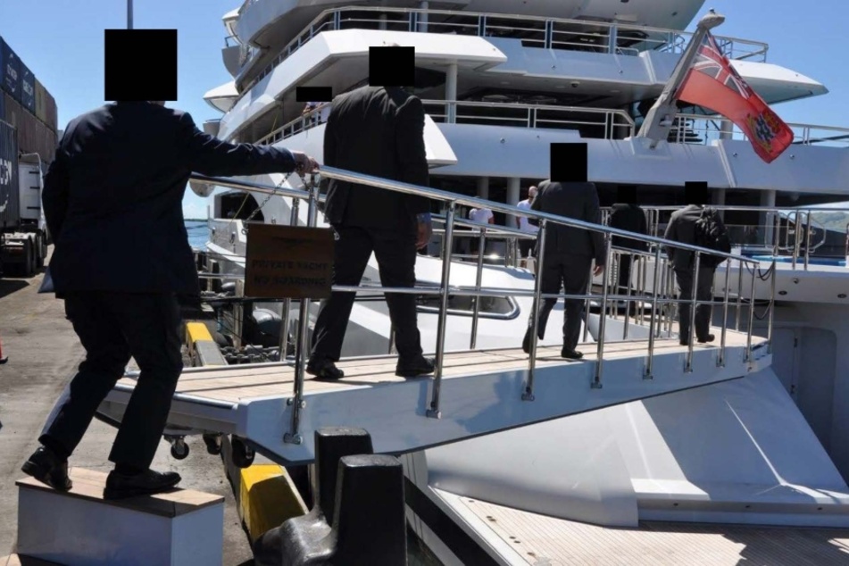 Lokale Behörden kommen an Bord der Mega-Yacht und beschlagnahmen das Schiff.